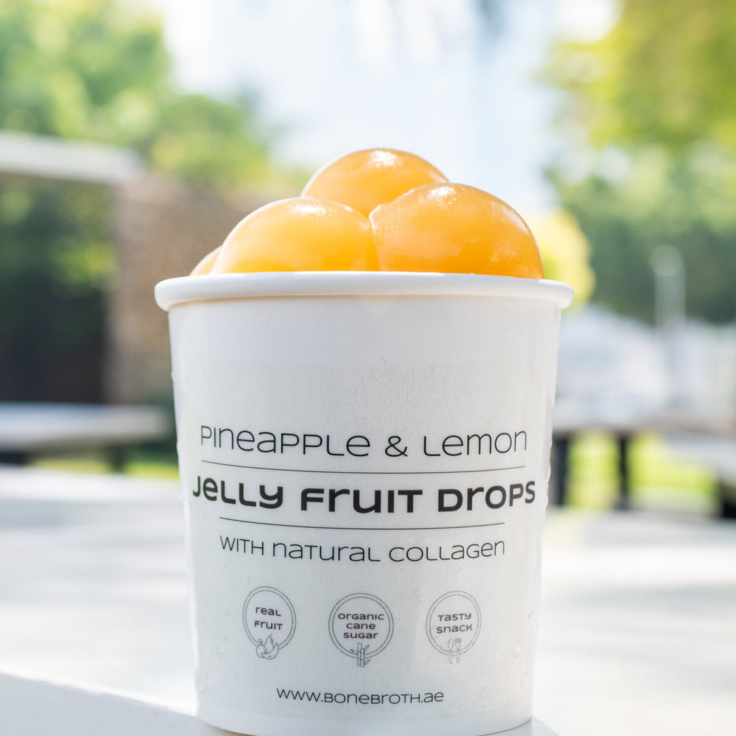 Container of pineapple and lemon jelly fruit drops with natural collagen on a blurred outdoor background